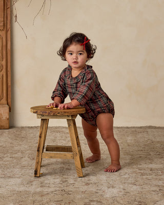 Noralee Adeline Romper - Winter Tartan
Child in plaid outfit standing on a wooden stool against a beige wall.