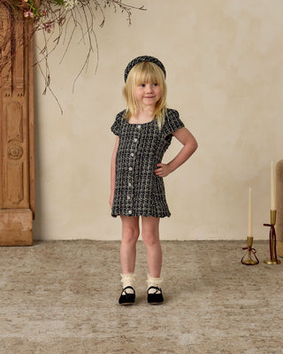 Noralee Gabrielle Dress - Black
Young girl in a black and white dress standing in a room with wooden floor and decorative elements.