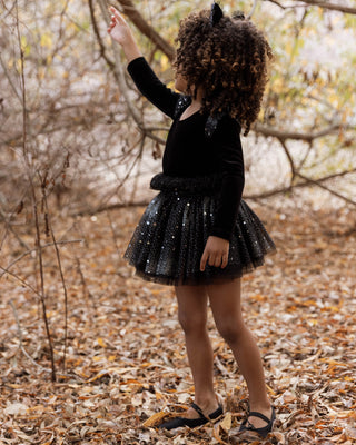 Noralee Lottie Tutu Set - Night Sky
Child in a black dress with sequin skirt standing in a forest setting