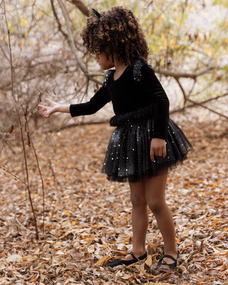 Noralee Lottie Tutu Set - Night Sky
Child in a black dress with sparkles standing in a forest with bare trees and fallen leaves.