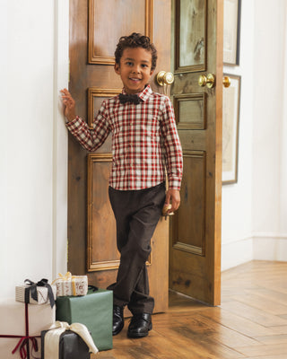 Noralee Bow Tie - Black
Noralee Harrison Button Down - Holiday Tartan
A young boy stands in a doorway wearing a red and white gingham long-sleeve shirt, a black bow tie, dark trousers, and black shoes. Gift boxes are stacked on the floor to his left.