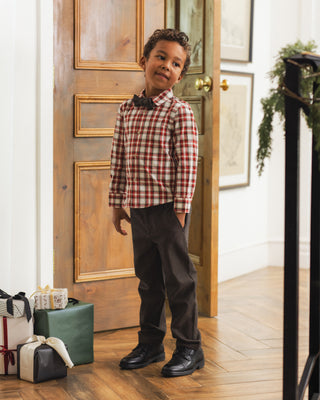 Noralee Harrison Button Down - Holiday Tartan
A young boy wearing a red and white plaid long-sleeve shirt, dark brown trousers, and black shoes stands in a doorway with wrapped gifts on the floor.