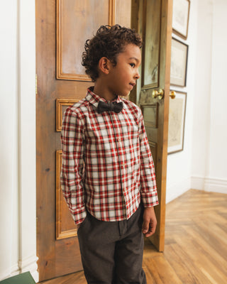 Noralee Bow Tie - Black
Noralee Harrison Button Down - Holiday Tartan
A young boy wearing a red and white plaid long-sleeve dress shirt with a black bow tie and dark gray trousers, standing in a doorway in a home interior.
