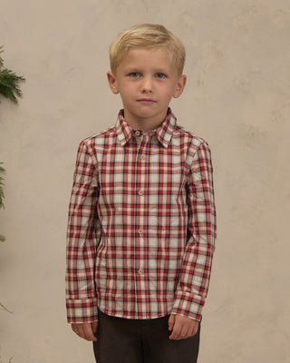 Noralee Harrison Button Down - Holiday Tartan
A young blond boy wearing a long-sleeve button-up shirt with a red and beige plaid pattern, paired with dark brown pants, standing against a textured beige wall.