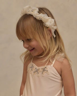 Noralee Gathered Headband - Pearl
Noralee Clementine Tutu - Pearl
A young blonde girl wearing a cream-colored ruffled flower crown headband and a matching cream dress with silver rhinestone embellishments, photographed against a neutral beige background.