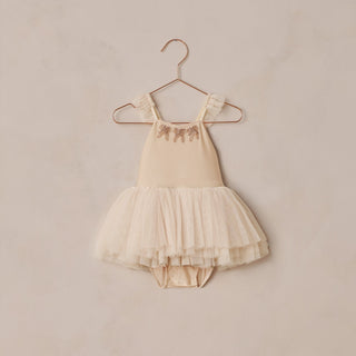 Noralee Clementine Tutu - Antique
Beige baby dress with a tutu skirt on a hanger against a beige wall