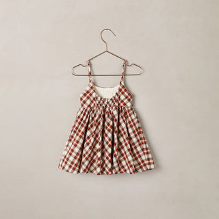 Noralee Betsy Dress - Holiday Tartan
A toddler girl's sleeveless dress with a red and white gingham pattern, featuring a smocked bodice and thin shoulder straps, hanging on a metal hanger against a neutral beige background.