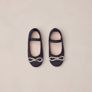 Noralee Ballet Flats - Black
Pair of black ballet flats with decorative bows on a beige background