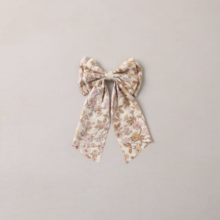 Noralee Alice Bow - Wildflower
A bow-shaped fabric hair accessory with a delicate floral pattern in muted beige, brown, and soft pink tones, centered on a plain light gray background.