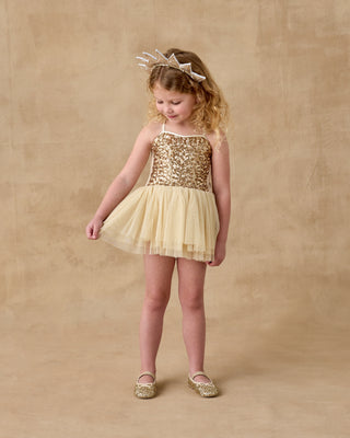 Noralee Clementine Tutu - Champagne
Young girl wearing a gold sequin dress and matching shoes on a beige background