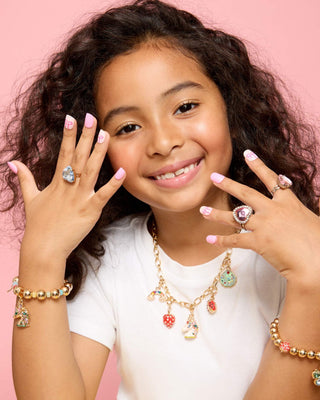 Super Smalls Heartfelt Press On Nail Kit
Young girl wearing multiple pieces of jewelry including rings and a necklace on a pink background