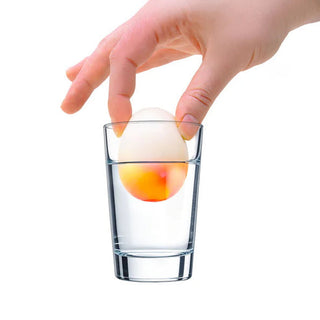 NeeDoh Dippin Dazzler
Hand placing a small ball into a clear glass of water on a white background