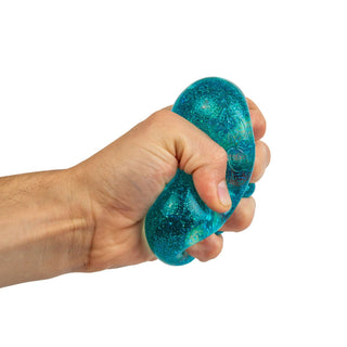 NeeDoh Glitter & Glow Nice CubeHand holding a blue glittery stress ball against a white background