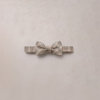 Noralee Bow Tie - Fall Plaid
A small plaid bow tie in beige, brown, and muted orange tones, centered on a light beige textured background.