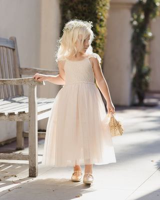 Noralee Camilla Dress - Pearl
Young girl in a white dress standing outdoors near a wooden bench.