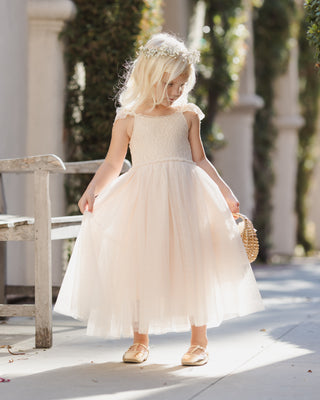Noralee Camilla Dress - Pearl
Young girl in a white dress standing outdoors with greenery in the background