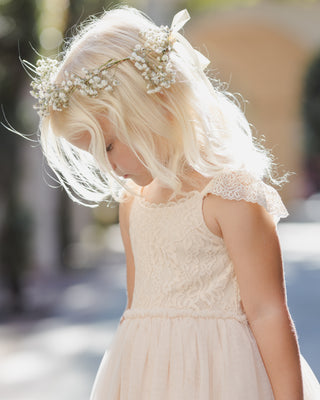 Noralee Camilla Dress - Pearl
Young girl in a white lace dress with a floral headband, outdoors.