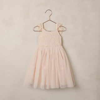 Noralee Camilla Dress - Pearl
Blush pink tulle dress on a hanger against a beige wall