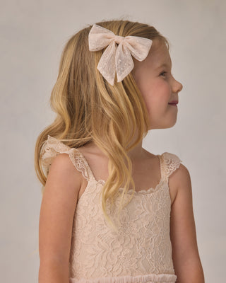 Noralee Camilla Tutu - Pearl
Young girl wearing a lace dress with a large bow in her hair against a plain background