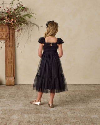 Noralee Clara Dress - Blackn 
Woman in a black dress standing in a room with decorative elements.