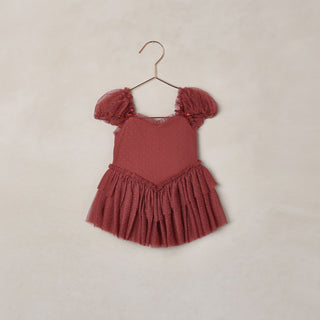 Noralee Gigi Tutu - Ruby
A dusty rose pink baby/toddler dress with puff sleeves and a ruffled tiered skirt, hanging on a metal hanger against a textured beige wall.