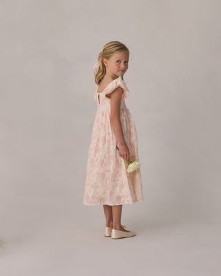 Noralee Hazel Dress - Blush English Rose
Young girl in a pink floral dress holding a white flower against a plain background
