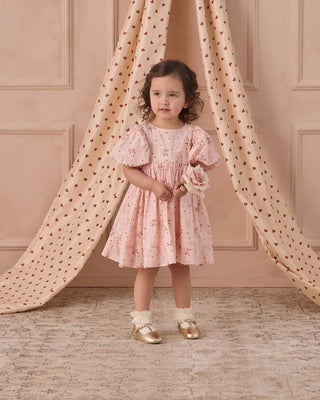 Noralee Luna Dress - Bouquet
Young girl in a pink floral dress standing in front of a pink wall with draped fabric.