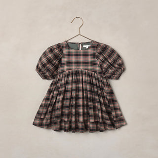 Noralee Luna Dress - Tartan
A toddler girl's short-sleeve dress with a puff sleeve and a gathered smocked bodice, featuring a brown, beige, and black plaid pattern. The dress is displayed on a metal hanger against a textured beige wall.