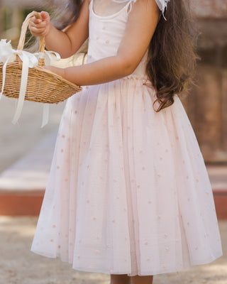 Noralee Poppy Dress - Blush
Young girl in a white dress holding a wicker basket with a blurred background