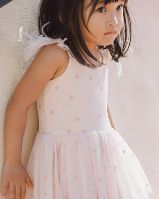 Noralee Poppy Tutu - Blush
Young girl wearing a white dress with pink polka dots against a neutral background