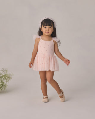 Noralee Poppy Tutu - Blush
Young girl in a pink dress with ruffled sleeves standing on a plain background