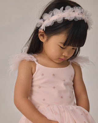 Noralee Poppy Tutu - Blush
Young girl wearing a pink dress with angel wings and a floral headband against a plain background