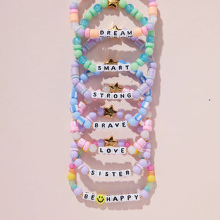 Little Words Project Kids bracelet with the word "Dream" engraved, featuring colorful beads and a silver clasp.
