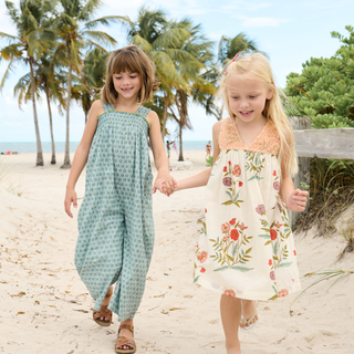 Pink Chicken Girls Courtney Dress - Rosewick Poppy
Two young girls holding hands on a sandy beach with palm trees in the background.