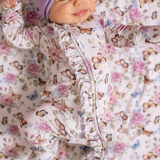 Posh Peanut Ruffled Zippered Footie - Mariselle
Baby in a floral and butterfly-patterned onesie with arms outstretched.