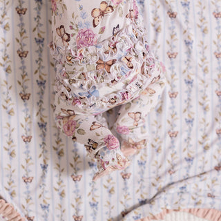 Posh Peanut Ruffled Zippered Footie - Mariselle
Floral and butterfly-patterned fabric draped over a surface with a striped background.