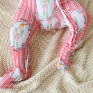 Posh Peanut Footie Zippered One Piece - Sable
Pink and white baby leggings with a pattern on a beige fabric background