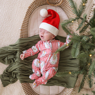 Posh Peanut Footie Zippered One Piece - Sable
Newborn baby in a Santa hat lying on a green blanket next to a Christmas tree.