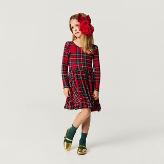 Posh Peanut Ruffled Twirl Dress - Red Tartan Plaid
Young girl wearing a red plaid dress with a large red bow on a white background