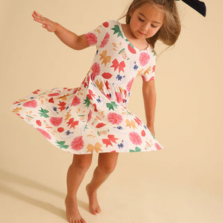 Posh Peanut Sabrina Criss-Cross Twirl Dress Young girl wearing a colorful floral dress on a beige background