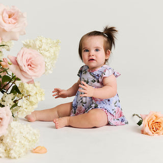 Posh Peanut Marion ruffled bodysuit dress shown on a model, featuring a tie-back design and playful ruffle details.