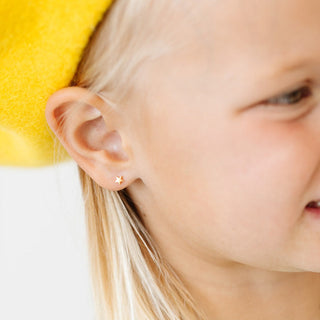 Pip Pop Post Earrings - Mini Star Stud
Close-up of a child's ear with a gold star-shaped earring against a blurred background