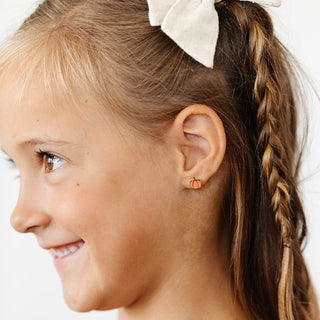 Pip Pop Post Earrings - Pumpkin
Close-up of a girl with a pumpkin earring on a white background
