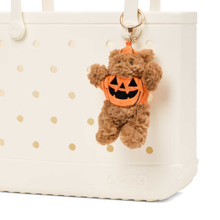 Bogg'd & Charmed - Pumpkin Bear
A brown plush teddy bear Halloween keychain or bag charm wearing an orange pumpkin costume, hanging from a gold ring on a white perforated plastic bag.
