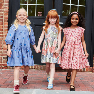Pink Chicken Girls Adaline Dress - Multi Striped Bows Pink Chicken Girls Peachy Dress - Pink Tiny Roses Three young girls holding hands in front of a brick building.