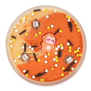 Peachybbies Cloud Slime - Monkey Bread A round decorative slime or playdough disc with a split orange and beige texture, topped with white and yellow sprinkles, dark chocolate-like pieces, and small cartoon face charms, centered on a white background.