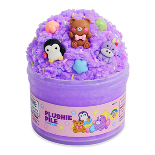 Peachybbies Cloud Slime - Plushie Pile A clear plastic tub filled with purple slime and topped with small plush toy figures and star-shaped sprinkles. The front label reads 'PLUSHIE PILE' with cartoon characters, and the product is photographed on a plain white background.