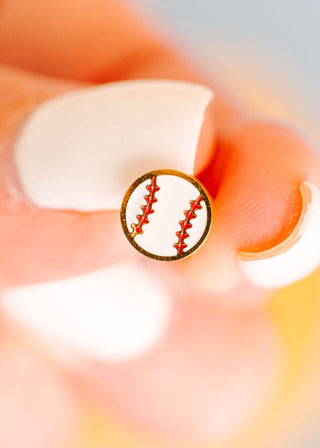 Pierced Co. Baseball Earrings
Close-up of a gold earring with a red and white design on a blurred background