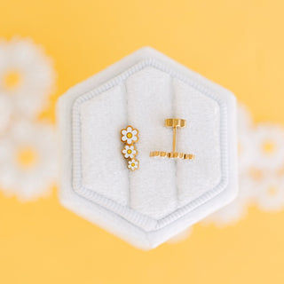 Pierced Co. Daisy Crawler Earrings
Gold earrings in a hexagonal white holder on a yellow background with floral elements.