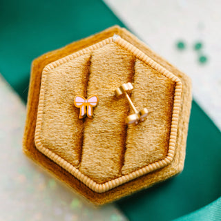 Pierced Co. Pink Bow Earrings
Hexagonal gold jewelry box with a bow-shaped earring on a green background